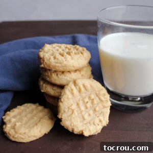 Peanut butter cookies with fork hash marks next to a glass of milk