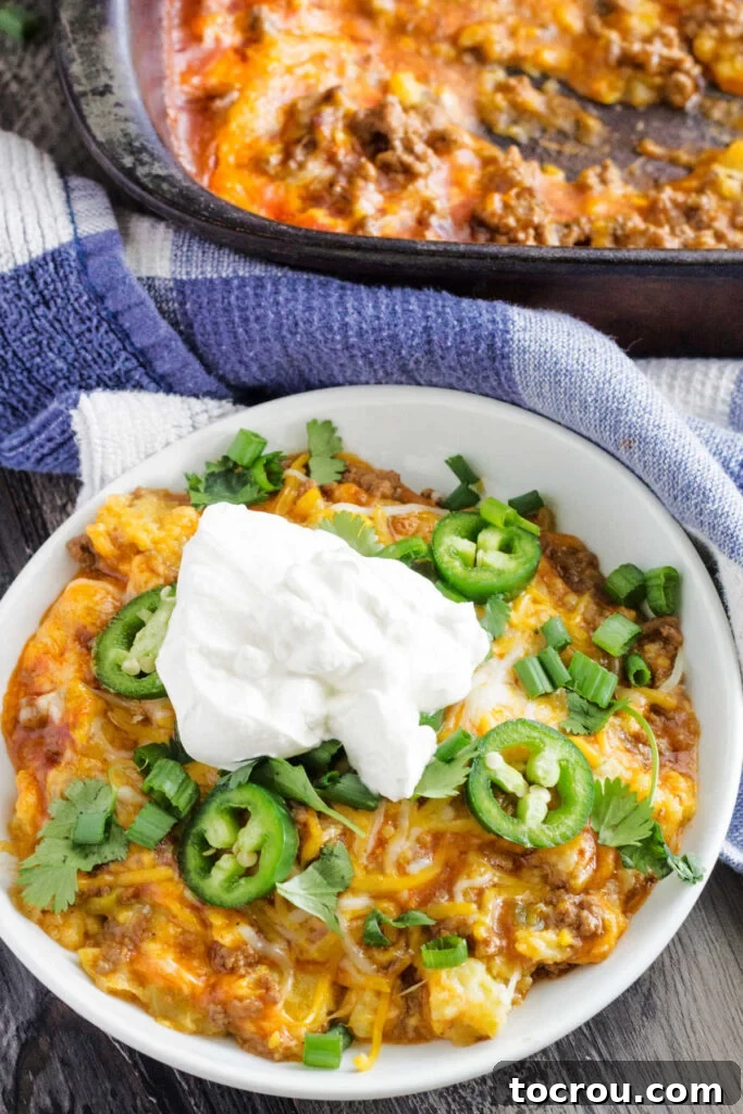 Plate of tamale pie topped with sliced jalapenos and a big dollop of sour cream.