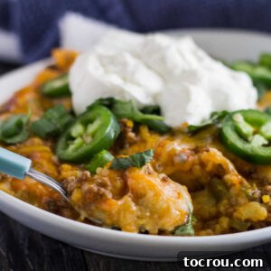 close serving of tamale casserole topped with jalapenos and sour cream, ready to eat.