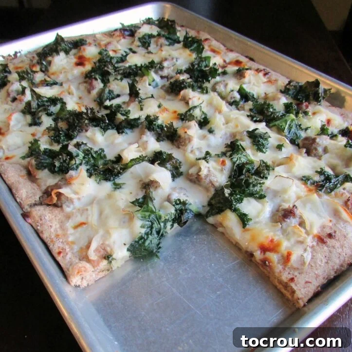 Zuppa Toscana Pizza on Sheet Pan Sheet pan filled with a freshly baked Zuppa Toscana pizza, generously topped with vibrant kale, flavorful Italian sausage, thinly sliced potatoes, and bubbling melted cheese, ready for serving.