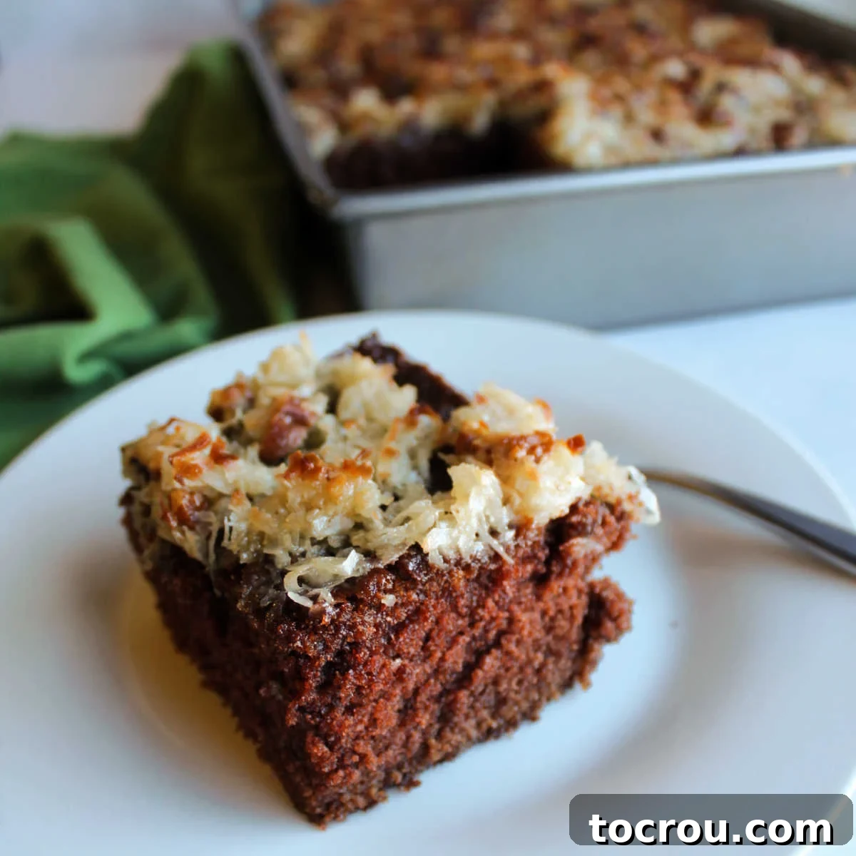 Decadent German Chocolate Cake Crowned with Broiled Coconut 2 Square piece of German chocolate cake topped with golden broiled coconut and pecan topping, glistening and ready to be enjoyed.