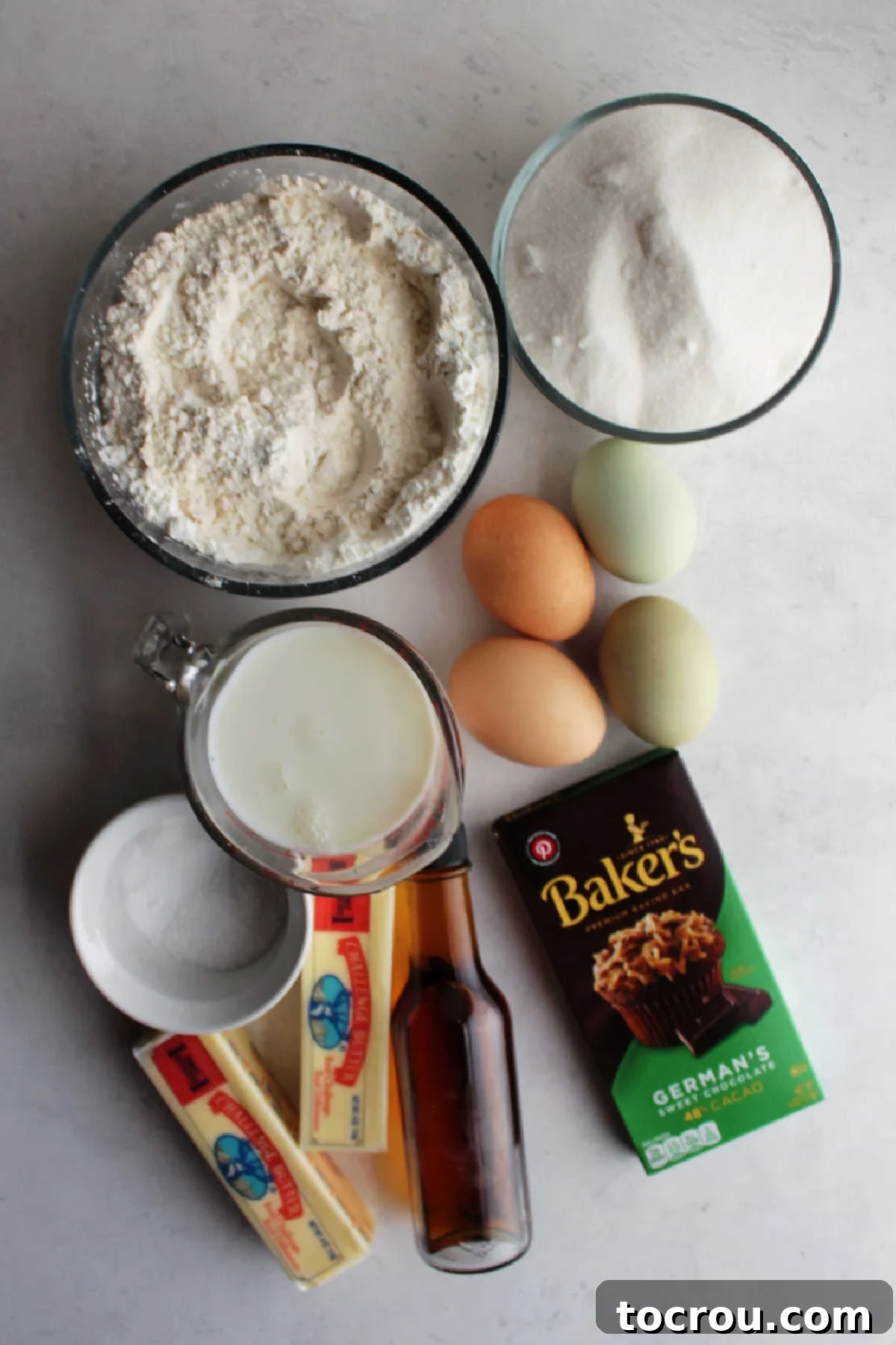 Decadent German Chocolate Cake Crowned with Broiled Coconut 3 Various ingredients for German chocolate cake including German chocolate squares, butter, vanilla extract, buttermilk, eggs, flour, granulated sugar, salt, and baking soda, neatly arranged on a counter before mixing.