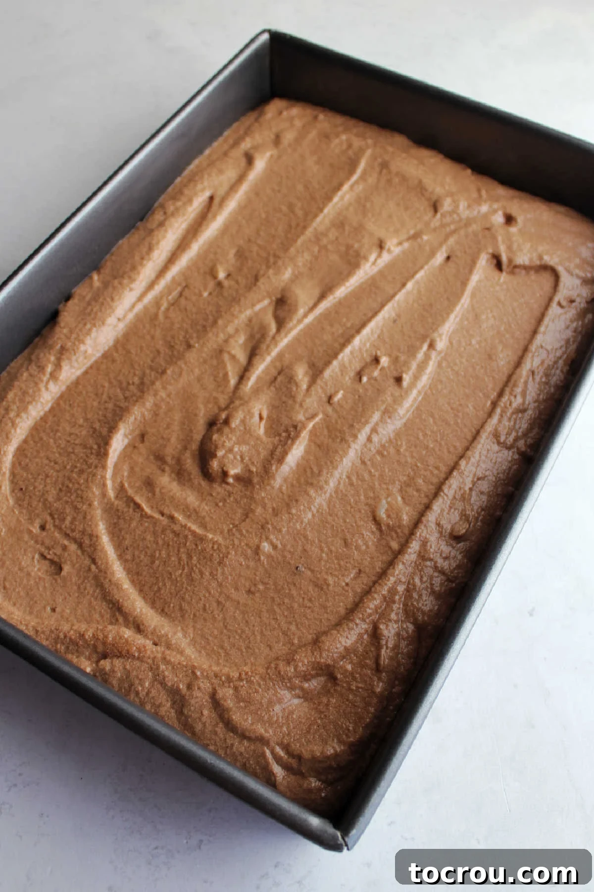 Decadent German Chocolate Cake Crowned with Broiled Coconut 5 Smooth German chocolate cake batter evenly spread in a 9x13-inch baking pan, ready to be placed in the oven.