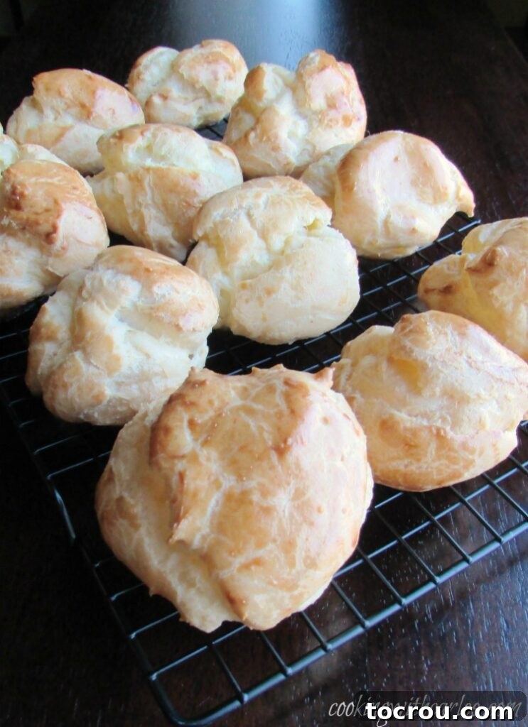 Golden-brown, puffed choux pastries cooling on a wire rack, ready for filling.