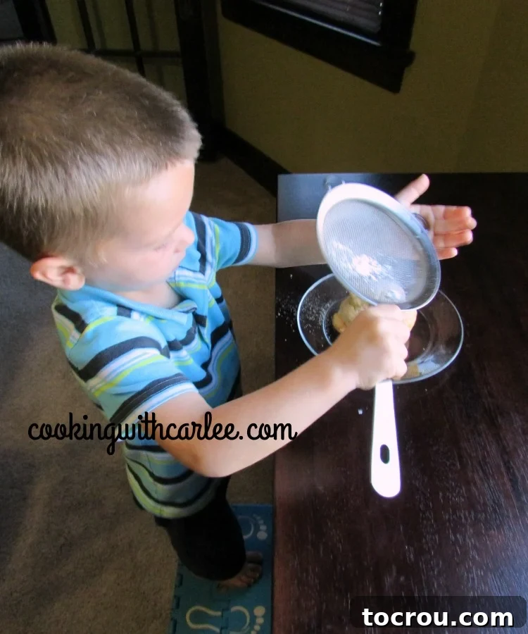 A child's hands gently dusting powdered sugar over a freshly filled pumpkin cream puff.