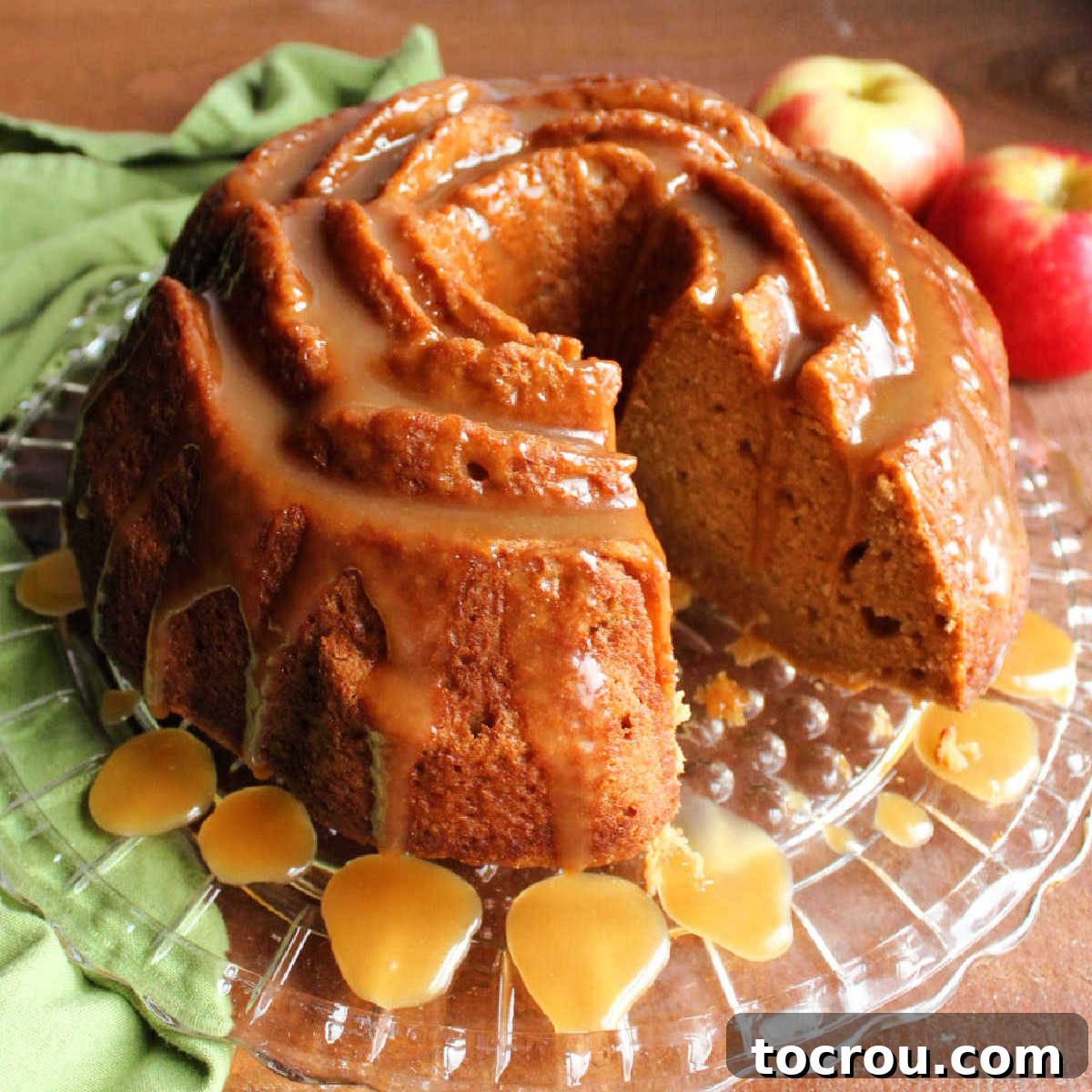 close up of caramel apple bundt cake Apple cider bundt cake drizzled with caramel sauce, missing one slice showing moist cake interior.
