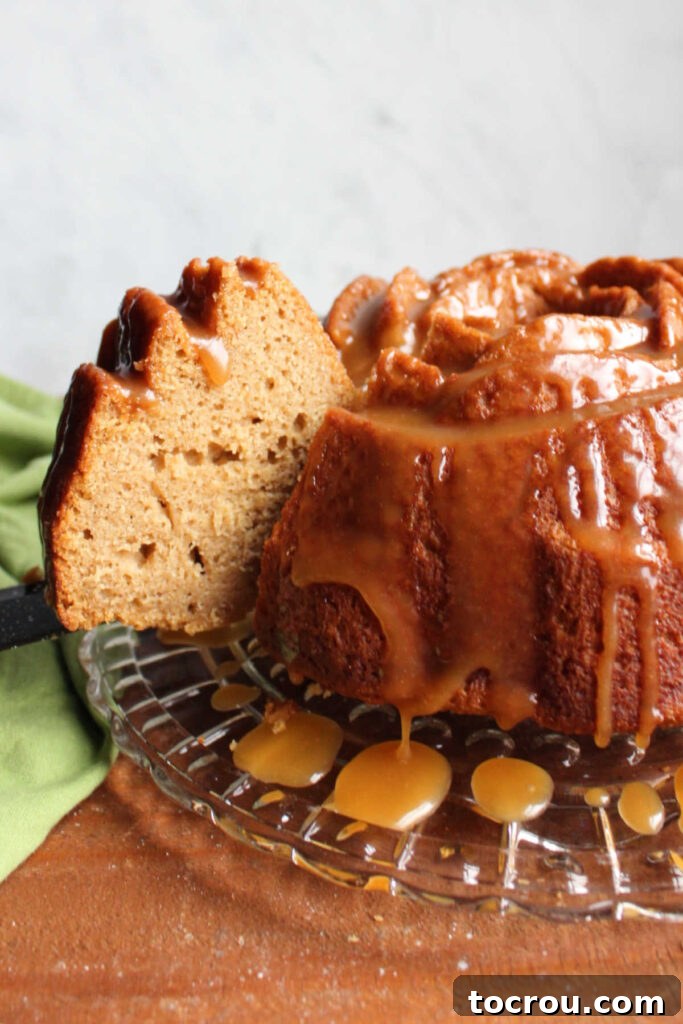 Cider Mill Bundt Cake 6 Slice of apple cider bundt cake being removed from the cake to be served showing dense pound cake texture and tan apple cinnamon color inside.