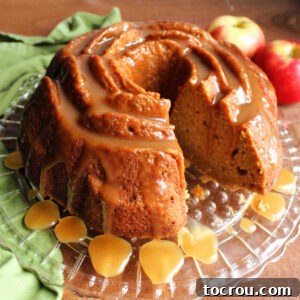 Cider Mill Bundt Cake 8 Apple cider bundt cake drizzled with caramel sauce, missing one slice showing moist cake interior.