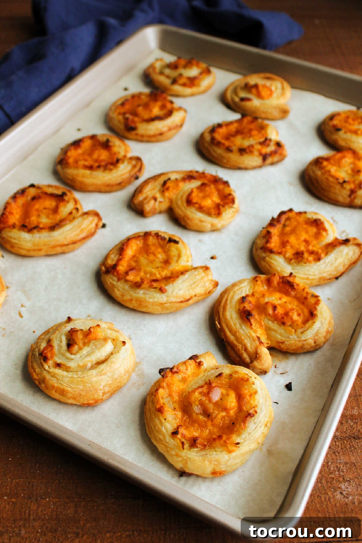 Freshly baked golden apple cheddar pinwheels, beautifully puffed and crusty, glistening straight out of the oven.