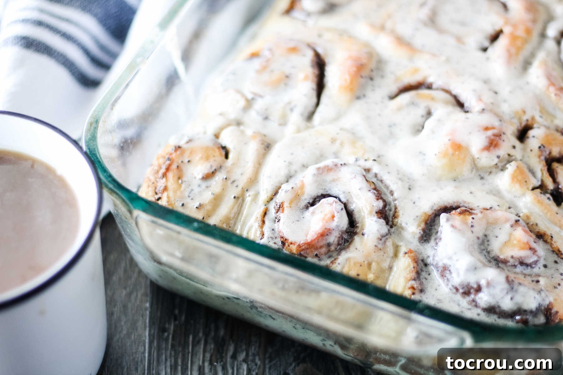 Irresistible Coffee & Cream Cinnamon Buns Pan of glazed coffee and cream cinnamon rolls that are ready to be served next to a mug of coffee.