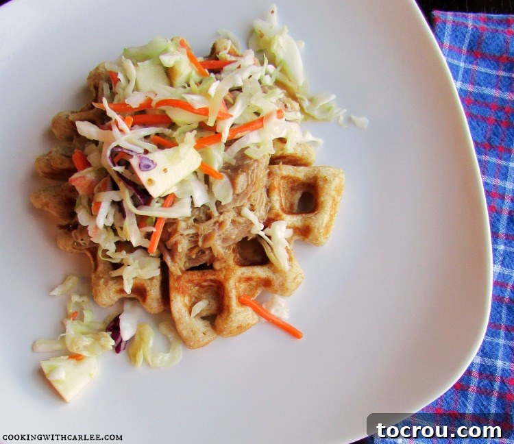 A crispy waffle generously topped with succulent pulled pork and a vibrant coleslaw, showcasing a savory meal idea.