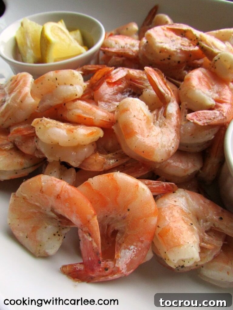 Close-up view of perfectly pink roasted shrimp nestled among bright yellow lemon wedges, highlighting the simple yet appealing presentation.