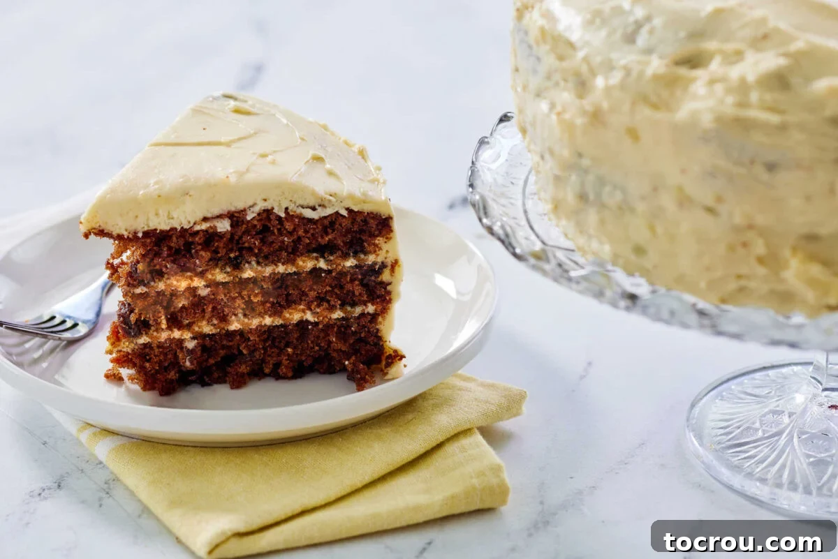 Slice of layered carrot cake with cream cheese frosting on plate, ready to eat.