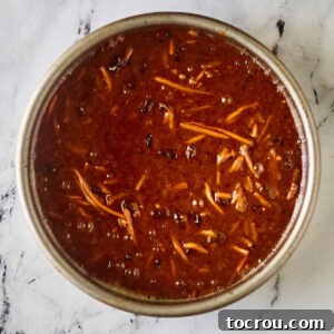 Bowl of carrot cake batter with shredded carrots and raisins suspended inside.
