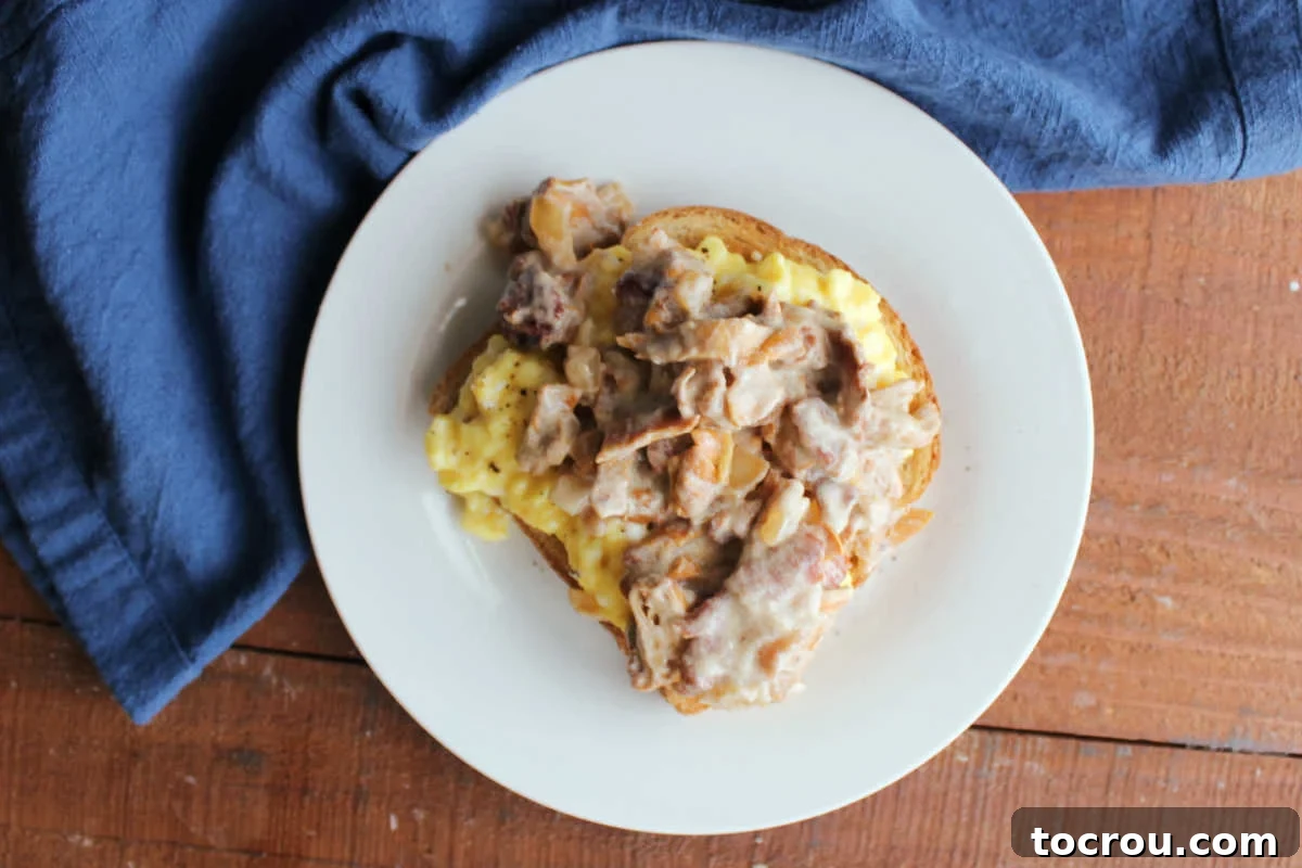 Small plate with a piece of toast topped with soft scrambled eggs topped with chanterelle mushrooms in a sour cream sauce with bacon and onions. A delicious and hearty breakfast or brunch option.