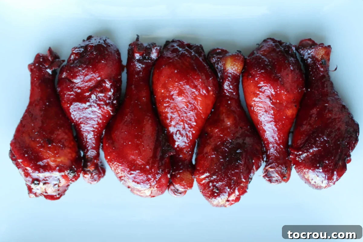 Platter of glossy red char siu grilled chicken legs, perfectly cooked and ready to serve.