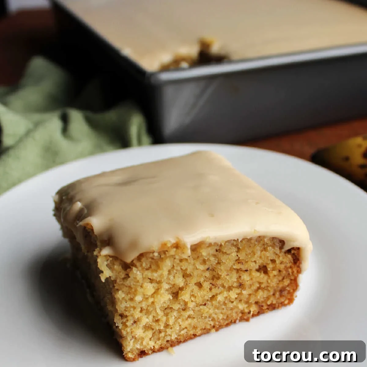 Smooth, sweet and creamy, this caramel frosting is easy to make and is a perfect topper to butter cake, chocolate cake, banana cake and more! Smooth brown sugar penuche icing on top of a piece of banana cake, showcasing a perfect finish.