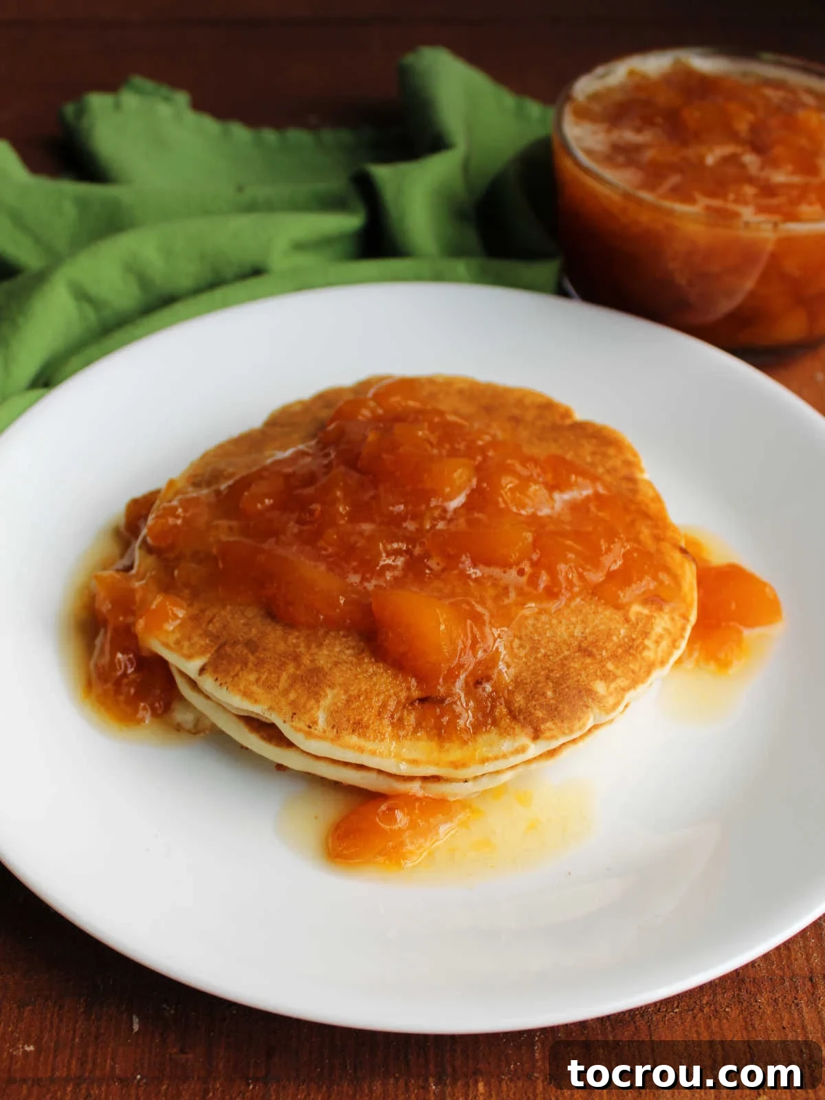 Peach Sauce on Pancakes A generous dollop of chunky peach sauce cascading over a towering stack of golden pancakes, a perfect breakfast treat.