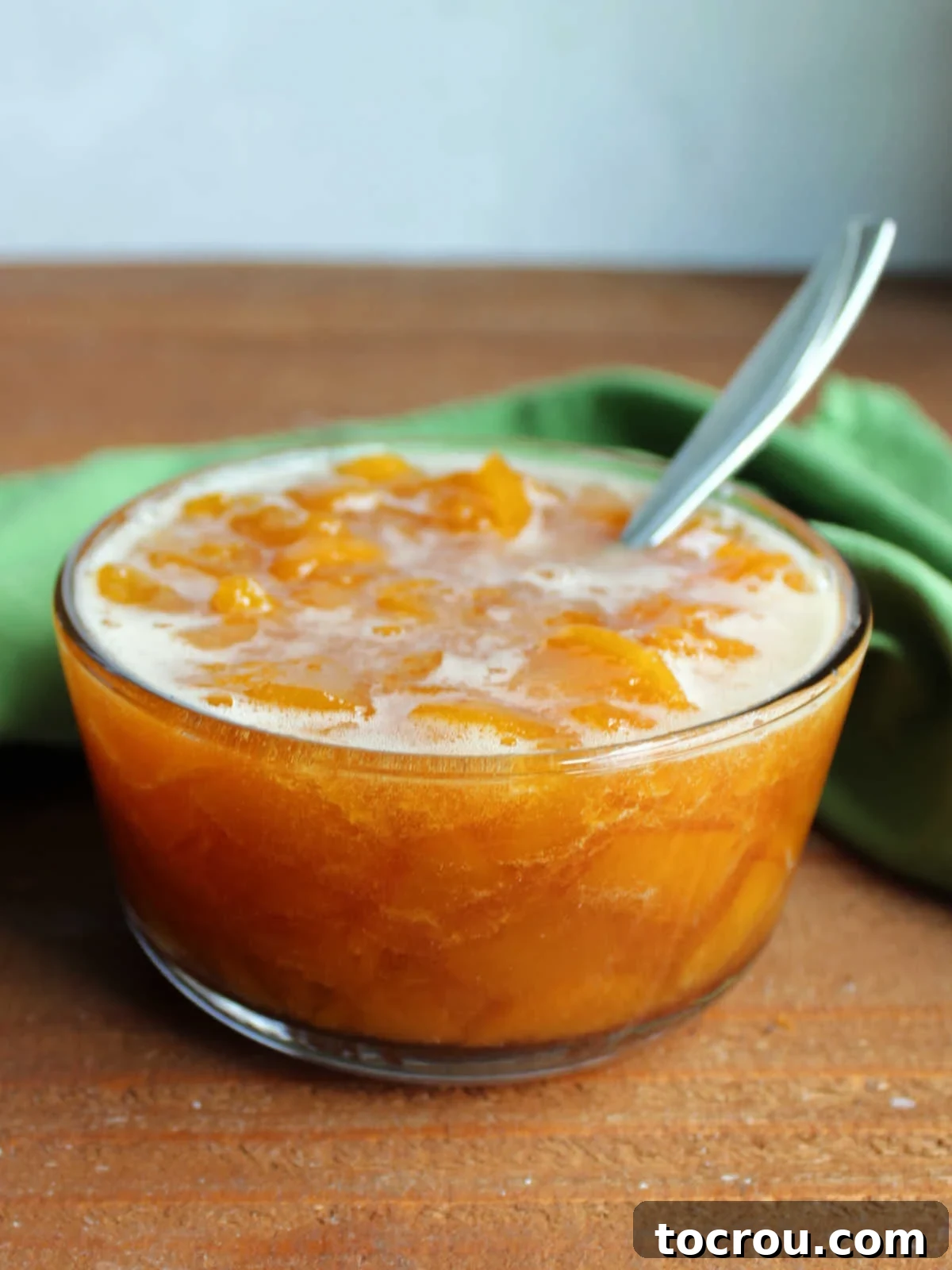 Chunky Peach Sauce A clear glass bowl showcasing a batch of homemade chunky peach sauce, ready to be served.