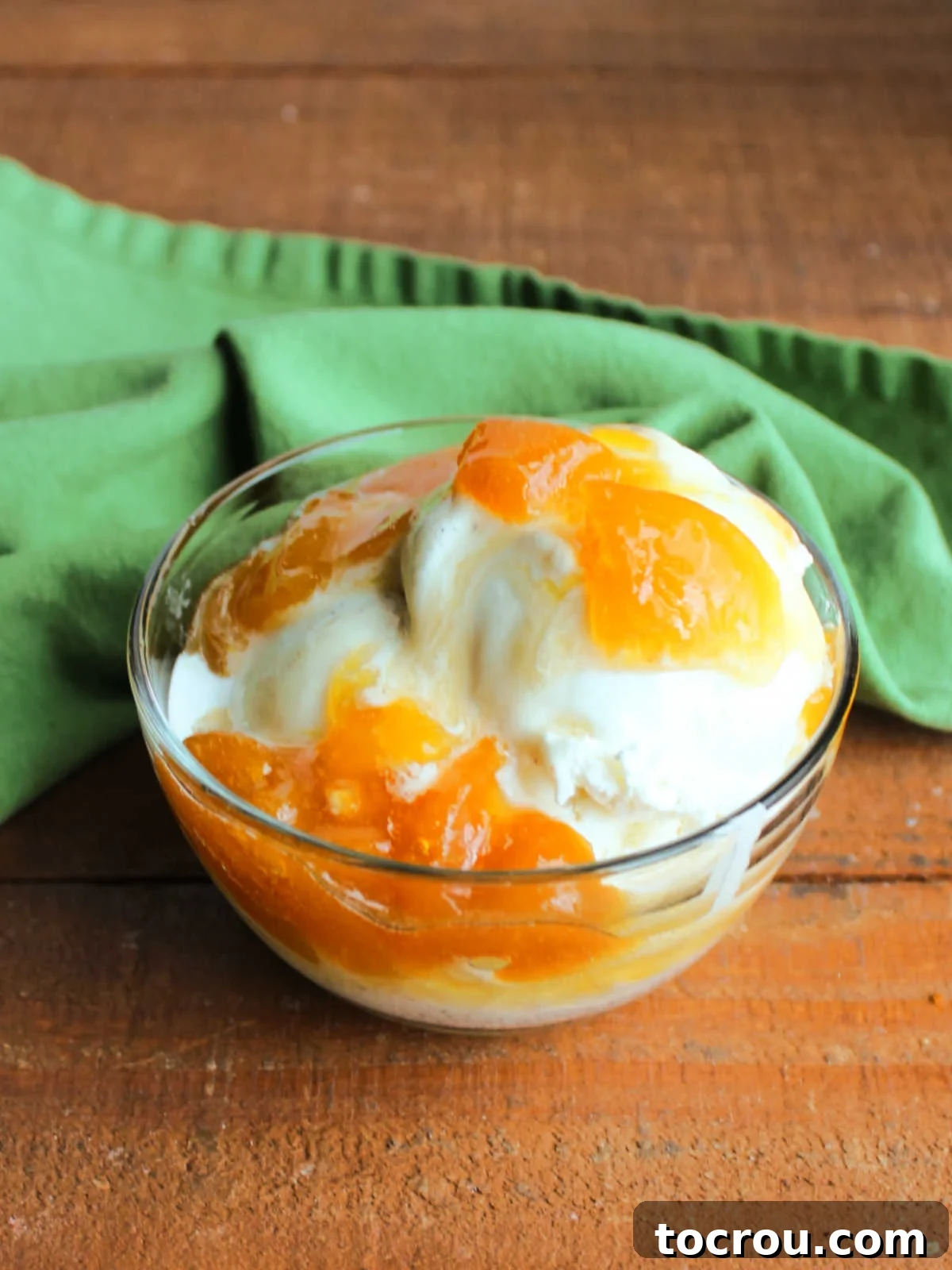 Peach Sauce on Ice Cream A scoop of vanilla ice cream generously covered with warm, chunky peach sauce, creating an irresistible dessert.