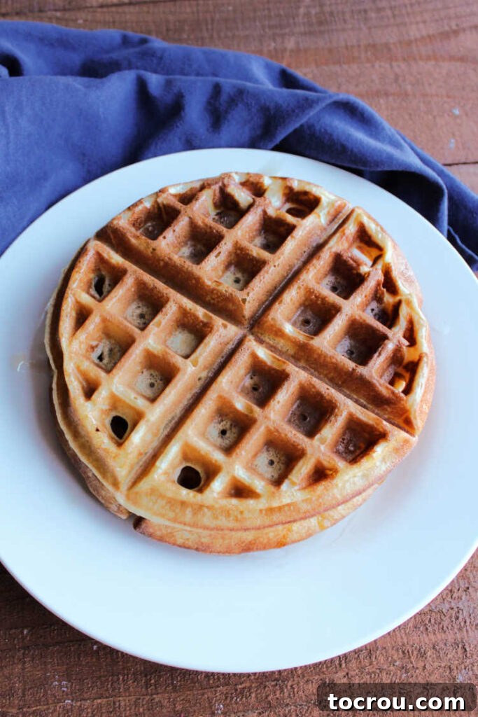 Stack of golden brown sourdough waffles on a plate, ready to be served.