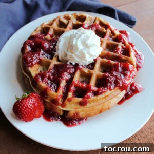 stack of sourdough waffles with strawberry sauce and whipped cream
