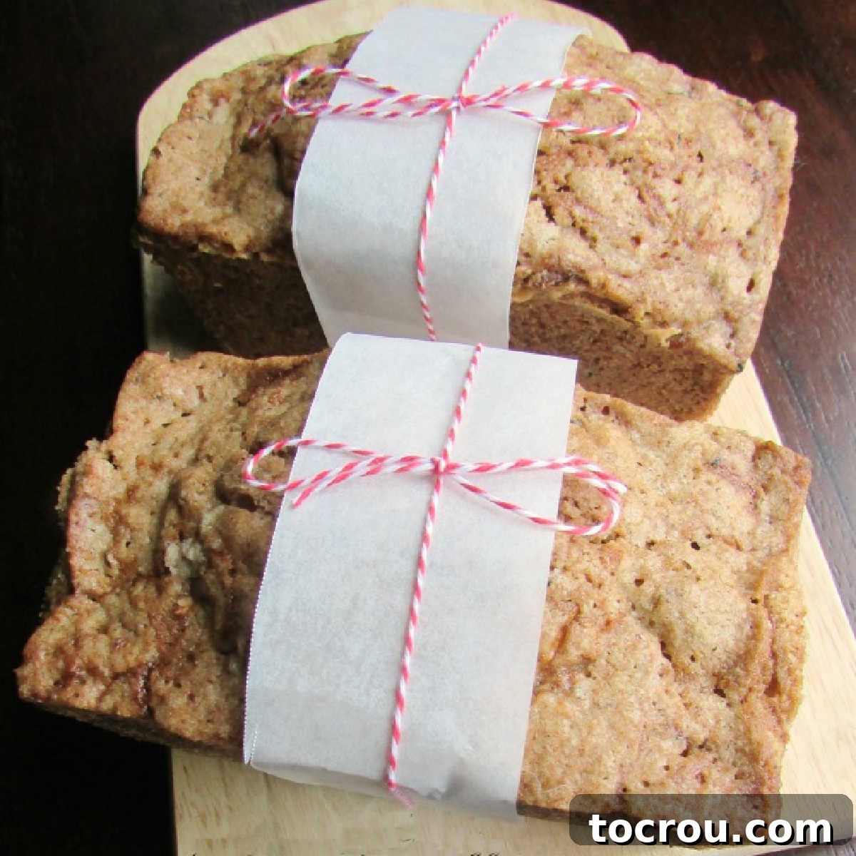Moist, flavorful mini zucchini bread loaves – the perfect balance of sweet and spice. Two small loaves of zucchini bread tied up with parchment paper and baker's twine, ready for gifting or enjoying.