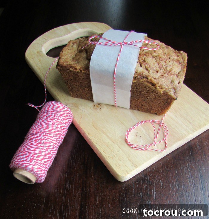 A golden-brown mini zucchini bread loaf, freshly baked. A perfectly baked mini loaf of zucchini bread, resting on a rustic cutting board, ready to be sliced.