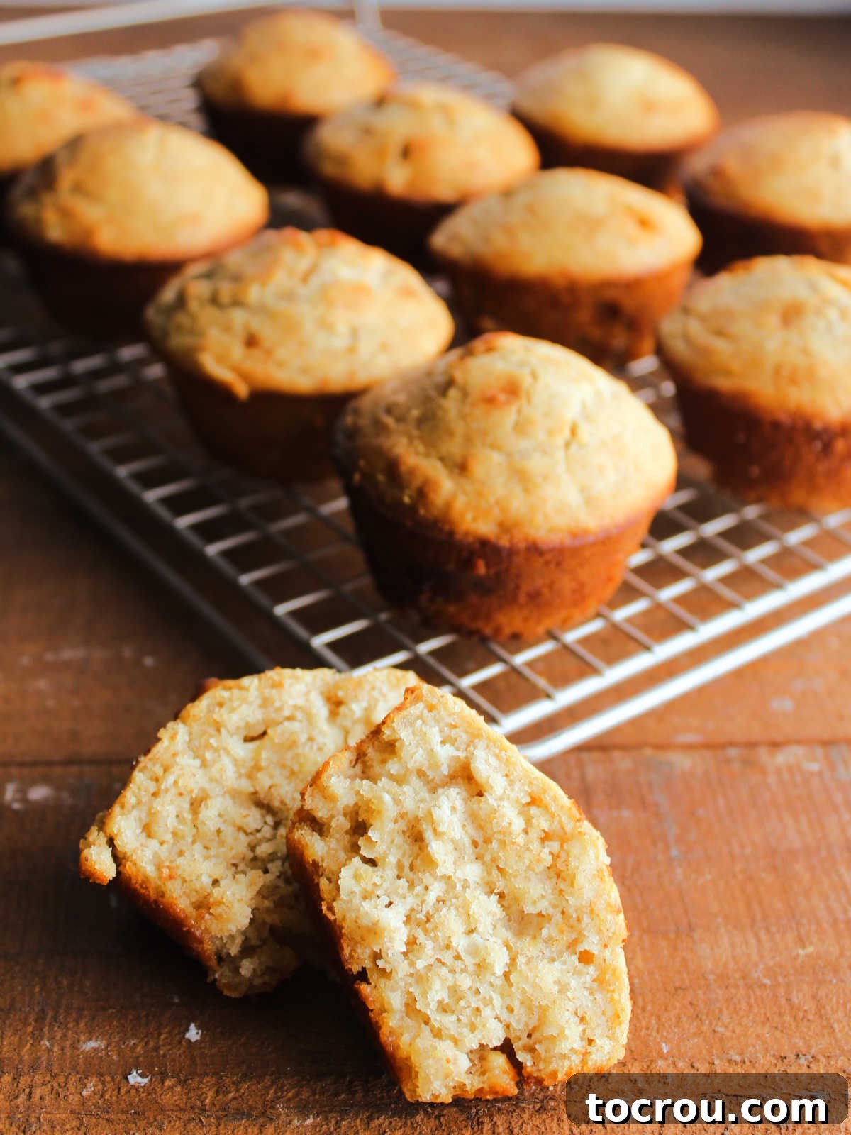 Artisan Sourdough Orange Dream Muffins 6 Muffins with nice rounded tops and golden brown edges on wire rack cooling, one cut in half showing the soft center of the muffin.