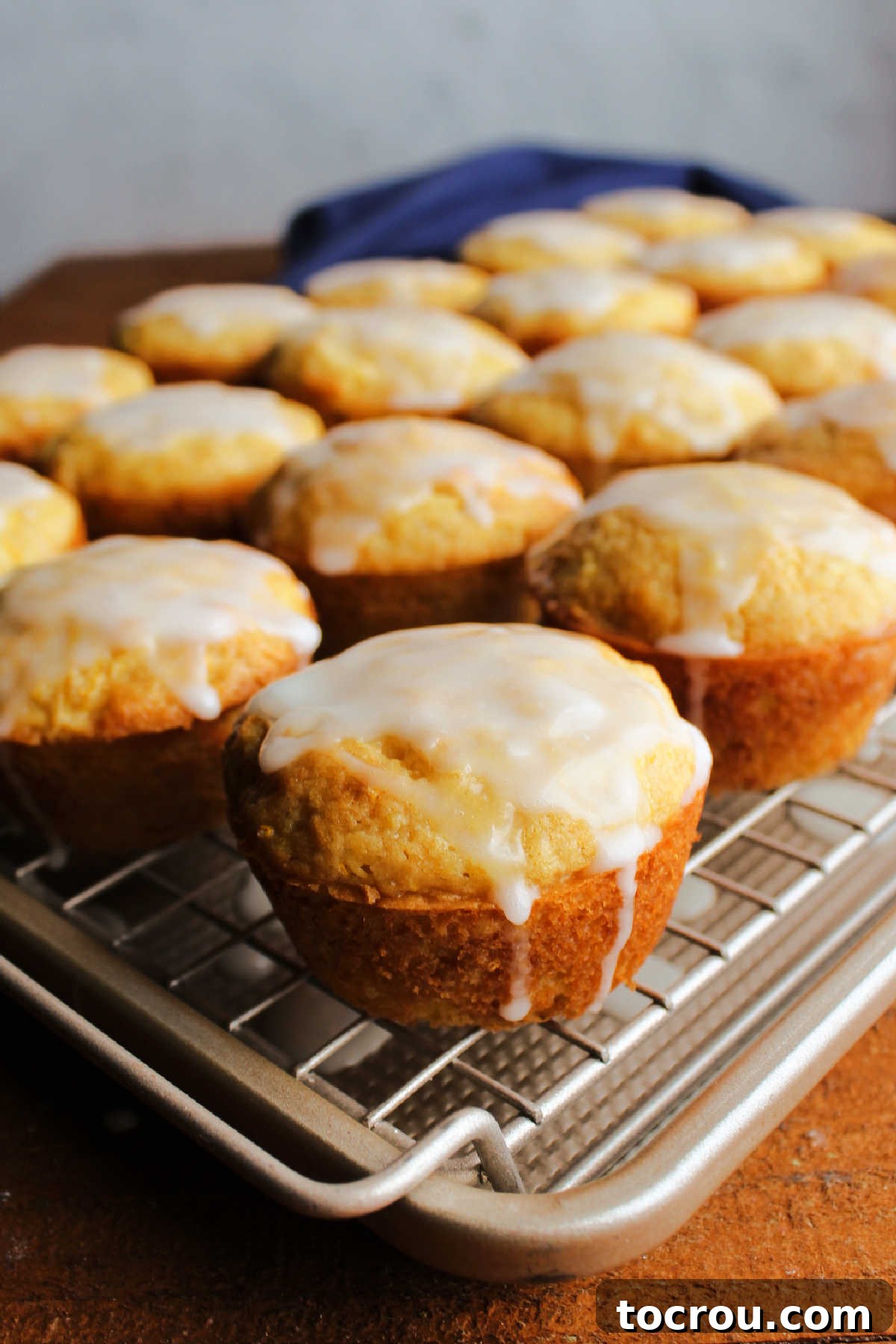 Glazed muffins cooling Glazed lemon summer squash muffins on wire rack over baking pan showing the drips going down the muffin onto the pan.