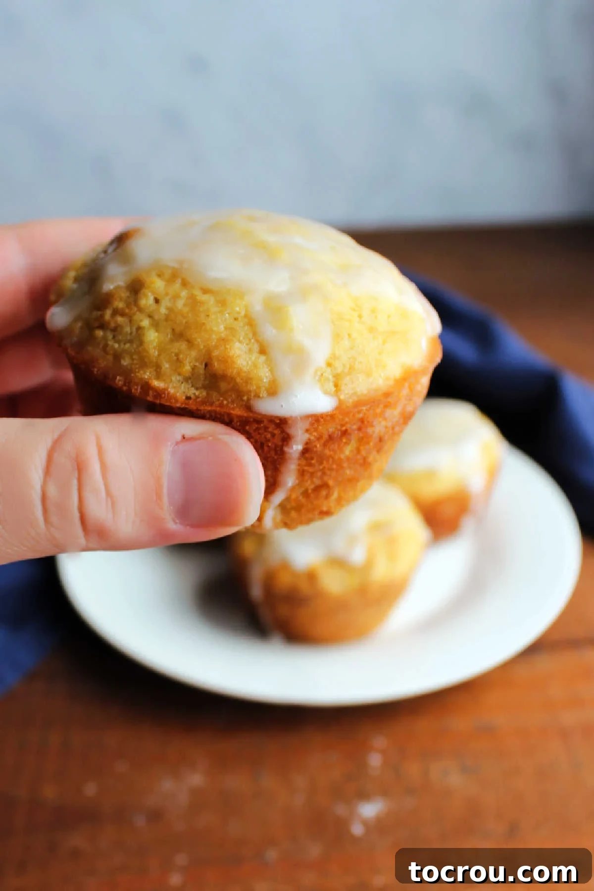 Enjoying a lemon squash muffin Hand holding a glazed summer squash muffin, ready to eat.