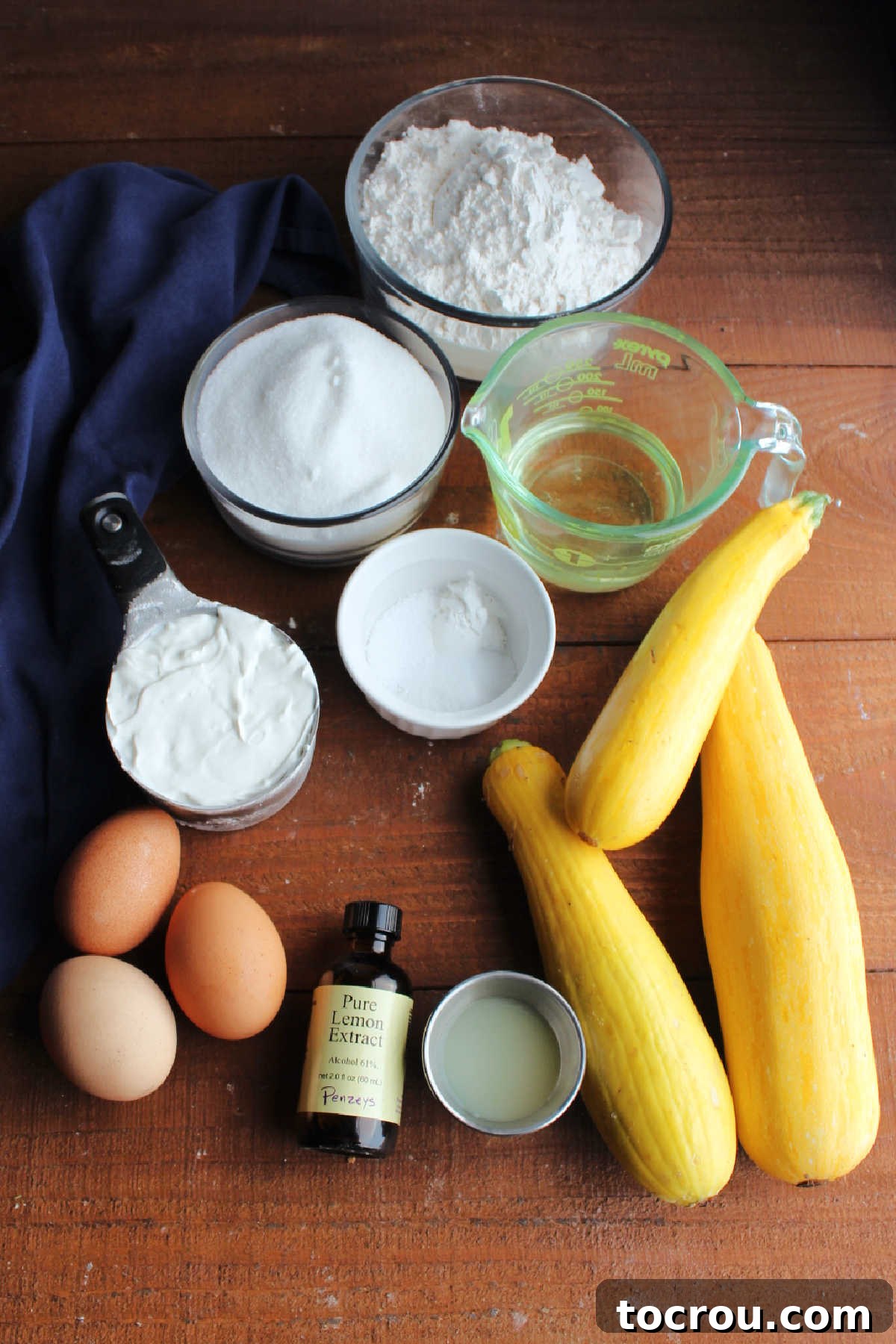 Muffin ingredients laid out Ingredients including summer squash, lemon juice, lemon extract, eggs, sour cream, oil, sugar, flour, baking powder and salt, ready to be made into muffin batter.