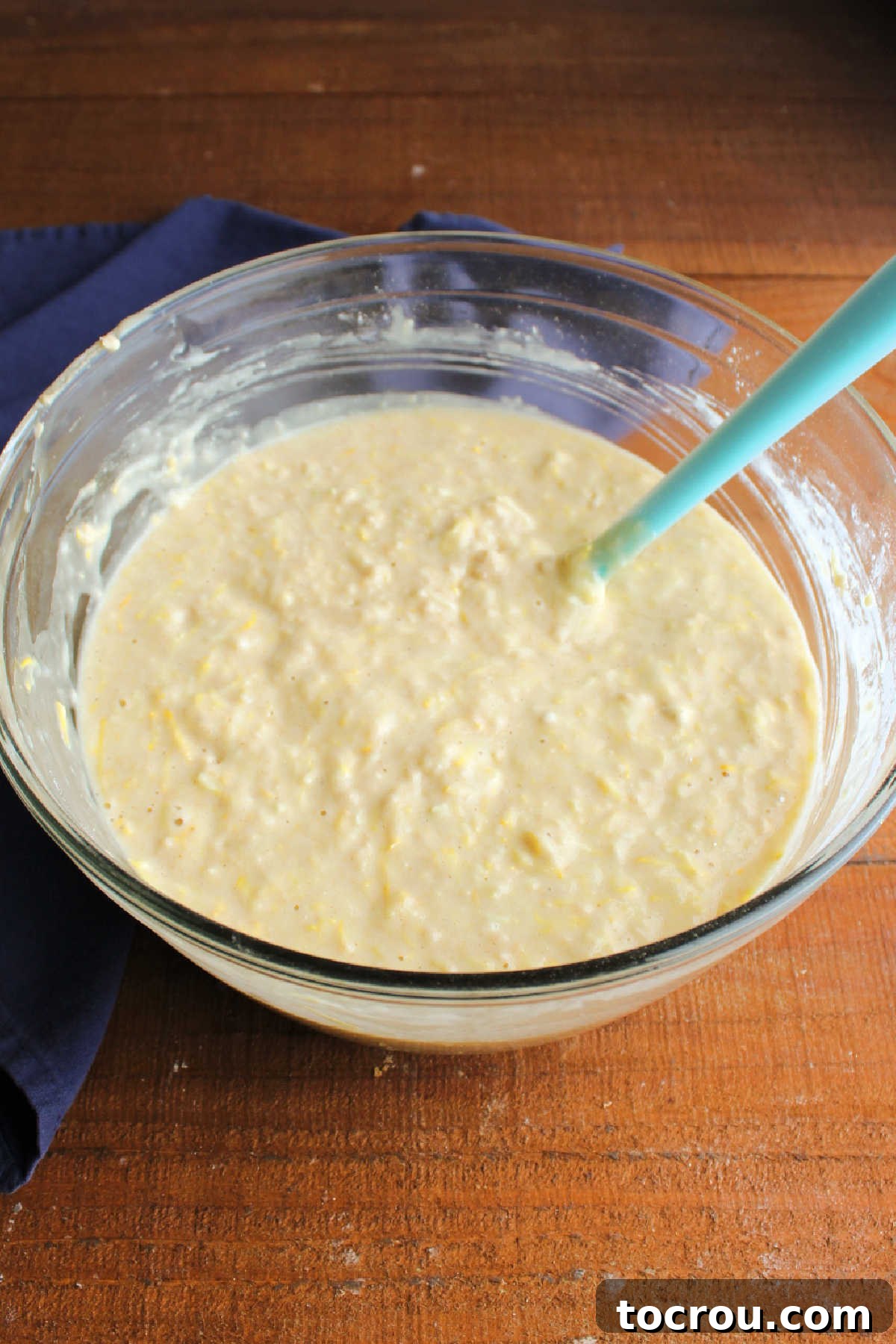 Muffin batter with shredded squash Mixing bowl filled with summer squash muffin batter with bits of shredded squash inside.