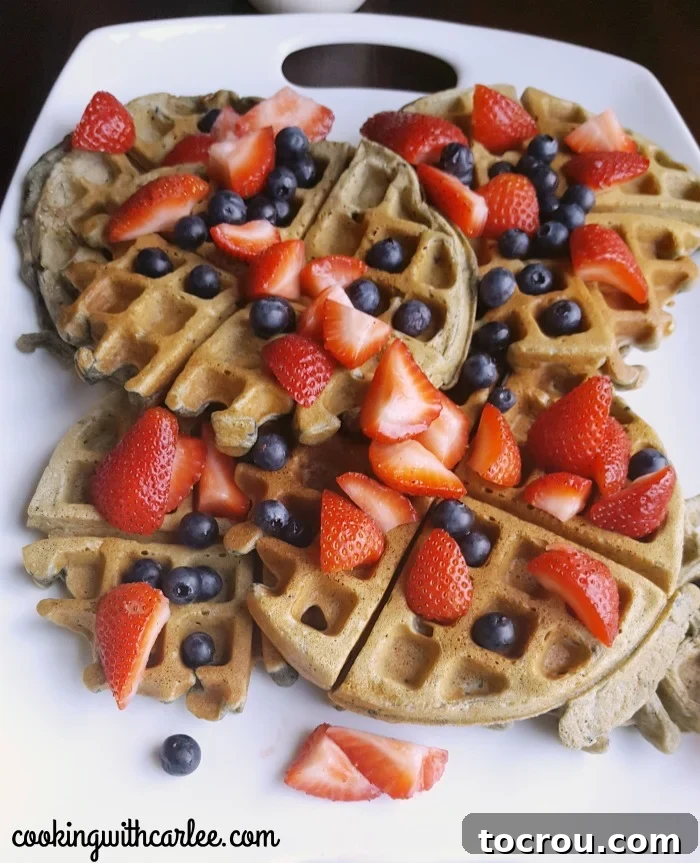 Delicious sourdough waffles with blueberries and fresh fruit. Close-up view of freshly made blueberry sourdough waffles, adorned with glistening fresh berries on top, highlighting their inviting texture and color.