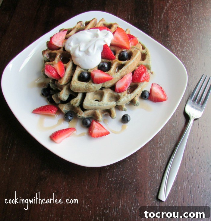 Sourdough blueberry waffles: The ultimate breakfast or brunch treat. A beautifully presented stack of blueberry sourdough waffles resting on a breakfast plate, generously topped with an assortment of fresh berries, a cloud of whipped cream, and a rich drizzle of maple syrup.