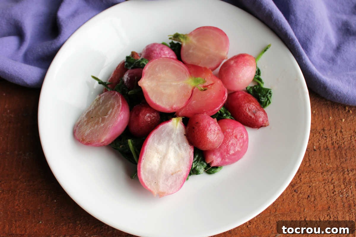 Plate of roasted radishes with wilted radish greens coated in a bit of melted butter, ready to eat. 