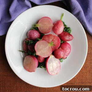 Plate of roasted radishes with wilted radish greens coated in a bit of melted butter, ready to eat.