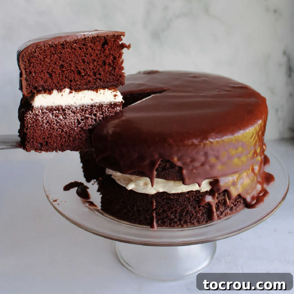 Chocolate Fudge Cream Delight 2 A glorious slice of homemade Ding Dong cake being lifted from the larger cake, showcasing the layers of rich chocolate cake, the creamy white vanilla filling, and the glistening dark chocolate icing. This image highlights the luscious texture and inviting appeal of the dessert.