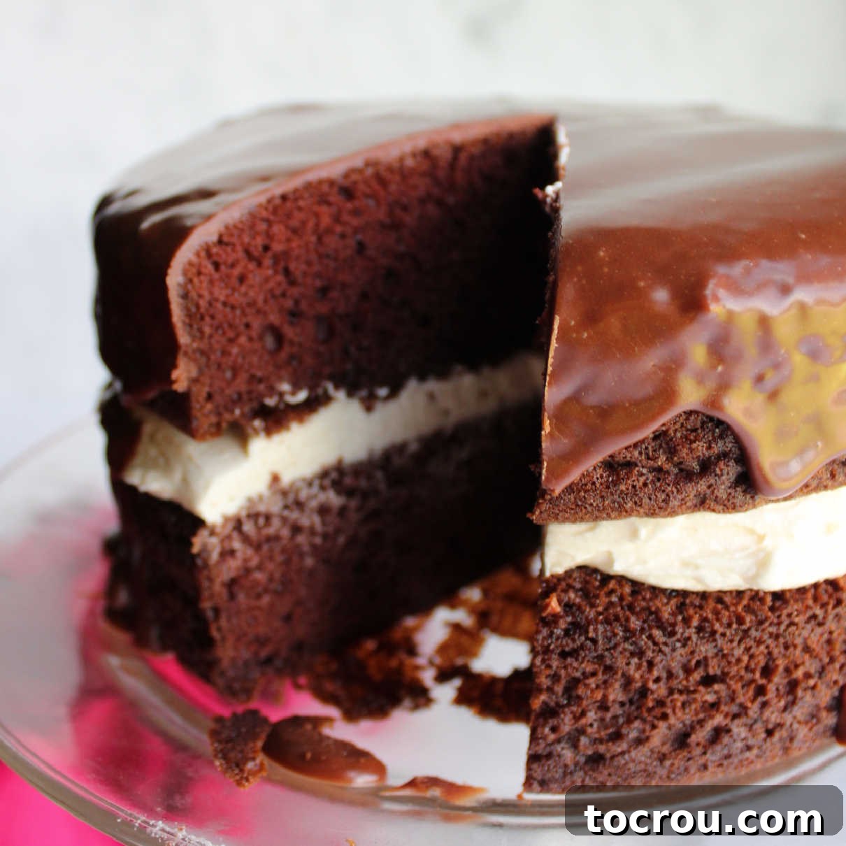 Chocolate Fudge Cream Delight 8 A stunning view of the chocolate Ding Dong cake with a slice already removed, clearly showing the distinct layers of chocolate cake and the thick, creamy white filling at its center. The dark chocolate icing drapes over the cake beautifully.