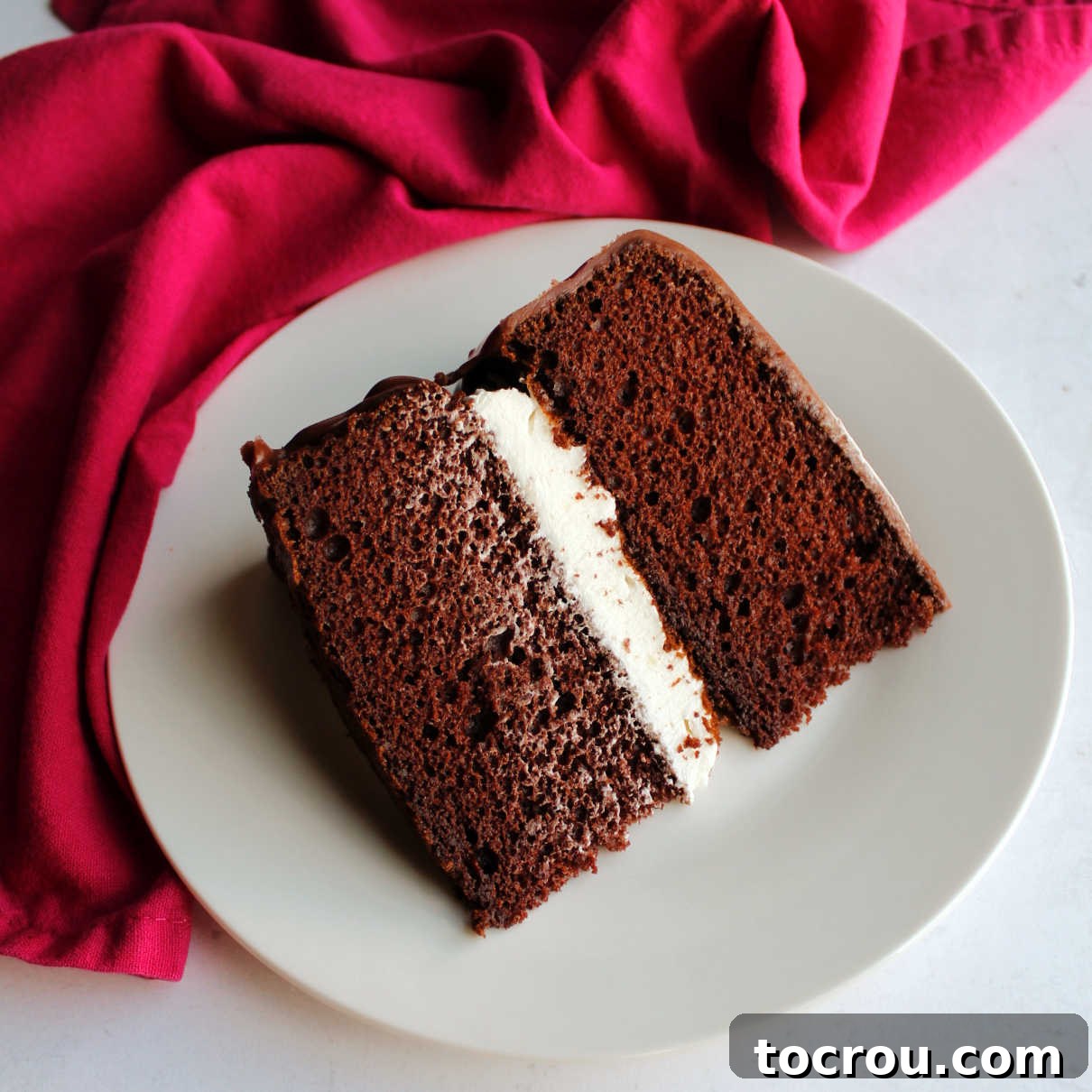 Chocolate Fudge Cream Delight 9 A single, perfectly cut slice of Ding Dong cake presented on a dessert plate, showcasing its moist chocolate layers, generous vanilla cream filling, and shiny chocolate icing, ready for enjoyment.