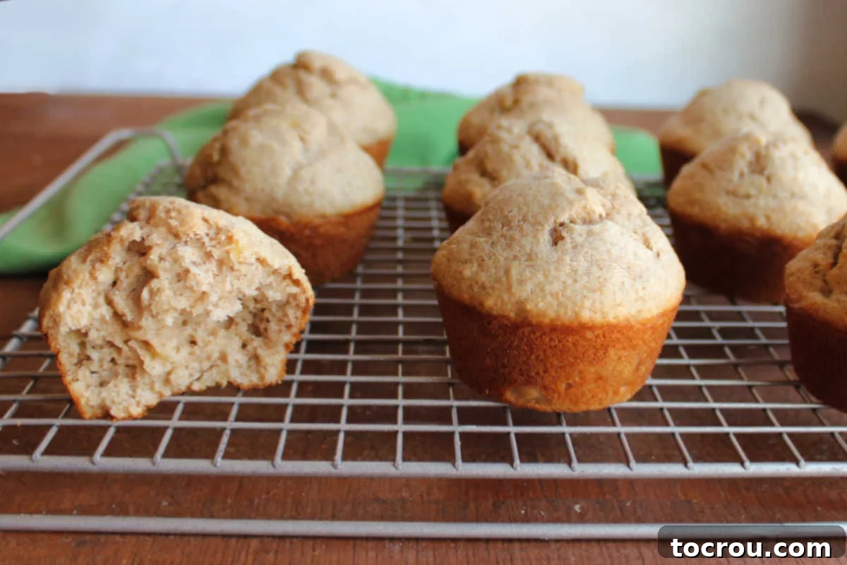 Tangy Sourdough Banana Muffins 2 Wire cooling rack with freshly baked sourdough banana bread muffins on it, showing their tall caps and light tan color.