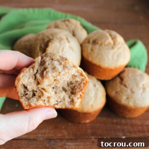 Hand holding half of a sourdough banana bread muffin showing the soft and airy interior.