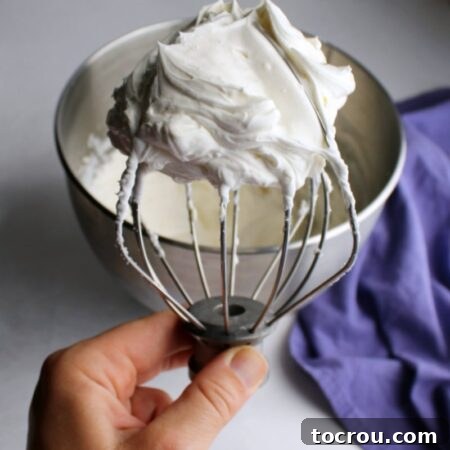 Cream Cheese Whipped Cream Recipe Image hand holding beater full of cream cheese whipped cream