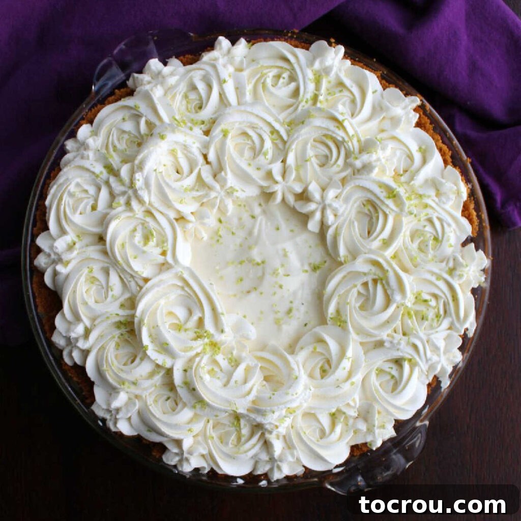 Key Lime Pie with Piped Whipped Cream whole key lime pie with whipped cream rosettes and flowers on top.