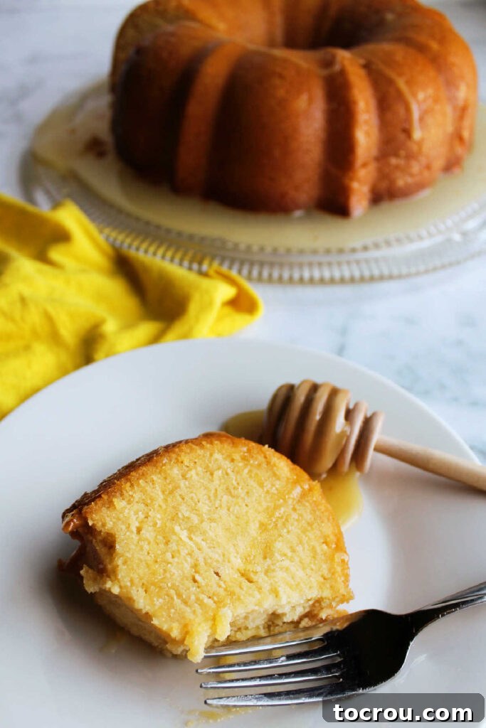 A fork resting next to a slice of golden honey lemon bundt cake with a bite missing, inviting you to taste its deliciousness.