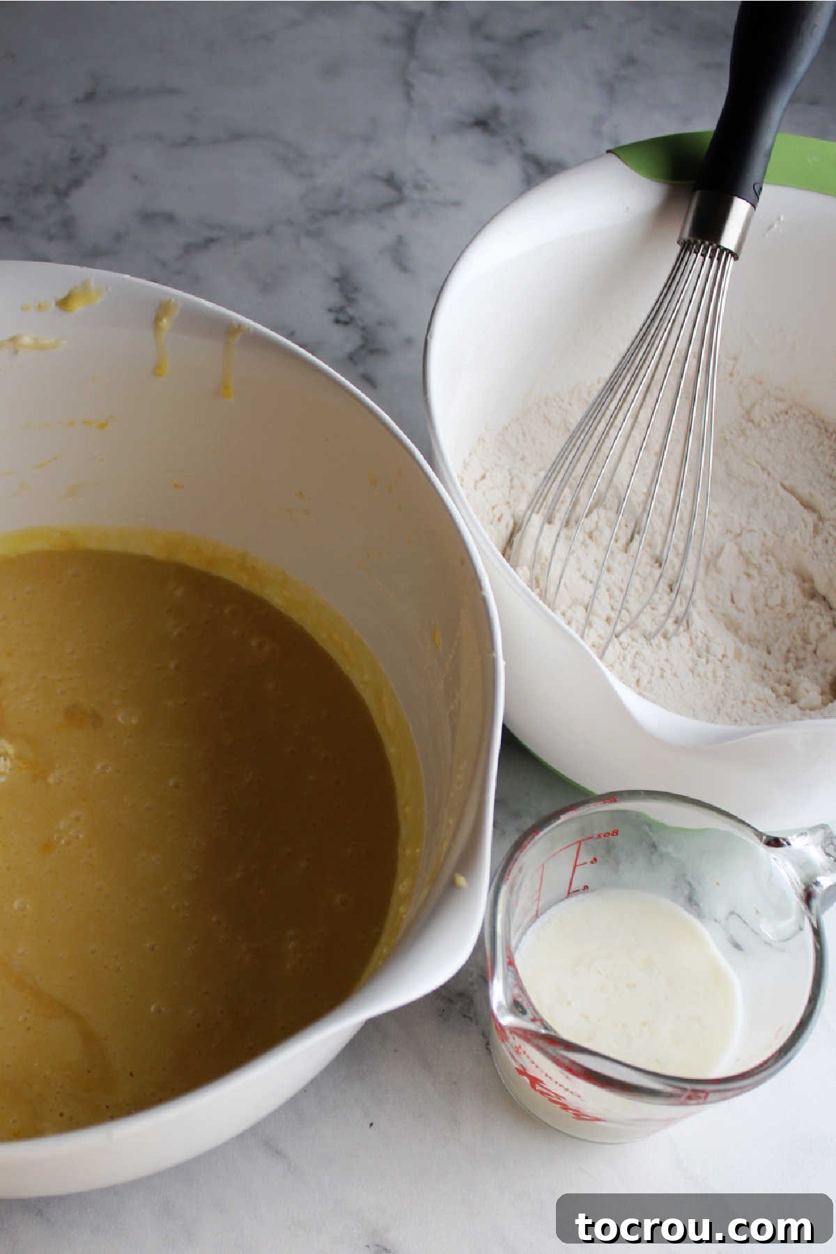 Bowl of dry ingredients, butter mixture, and buttermilk ready to be combined into a delicious honey lemon cake batter.