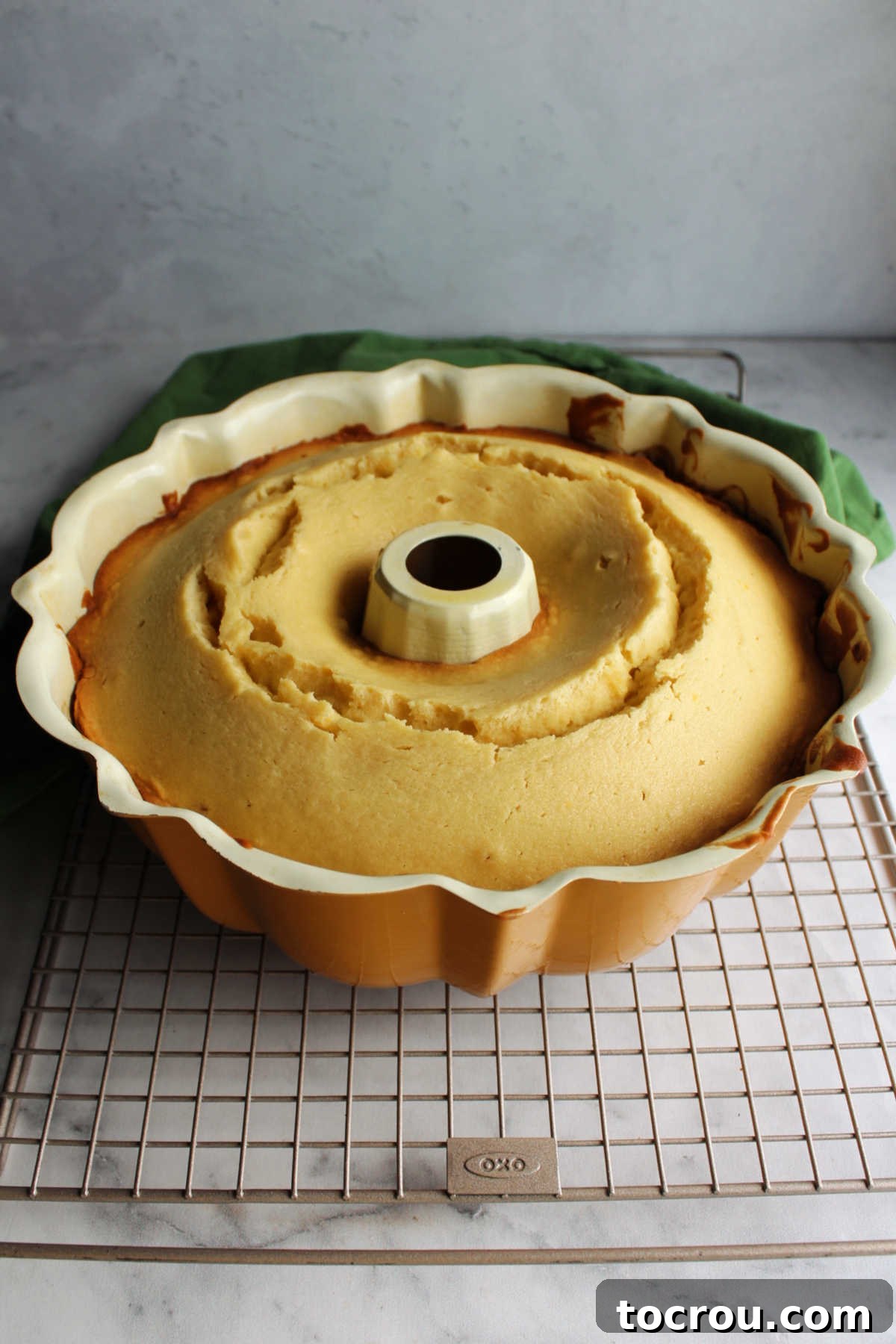 Warm honey lemon bundt cake fresh from the oven, cooling gracefully in its pan on a wire rack, steam gently rising.