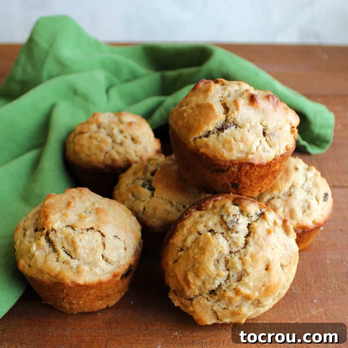 A warm pile of freshly baked oatmeal raisin sourdough muffins, golden brown and inviting.