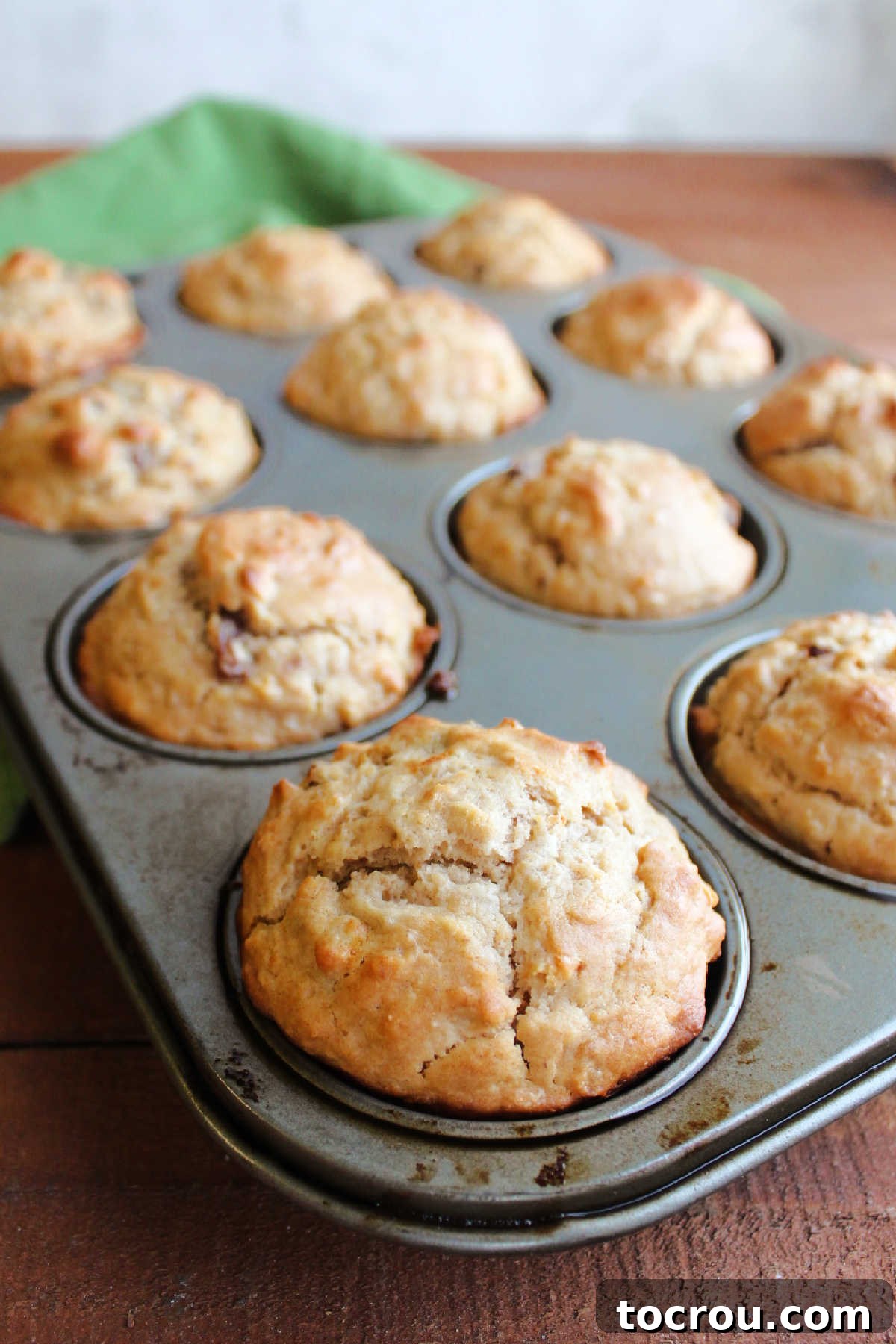 A pan of freshly baked oatmeal raisin sourdough muffins, showcasing their perfectly golden tops and inviting texture.