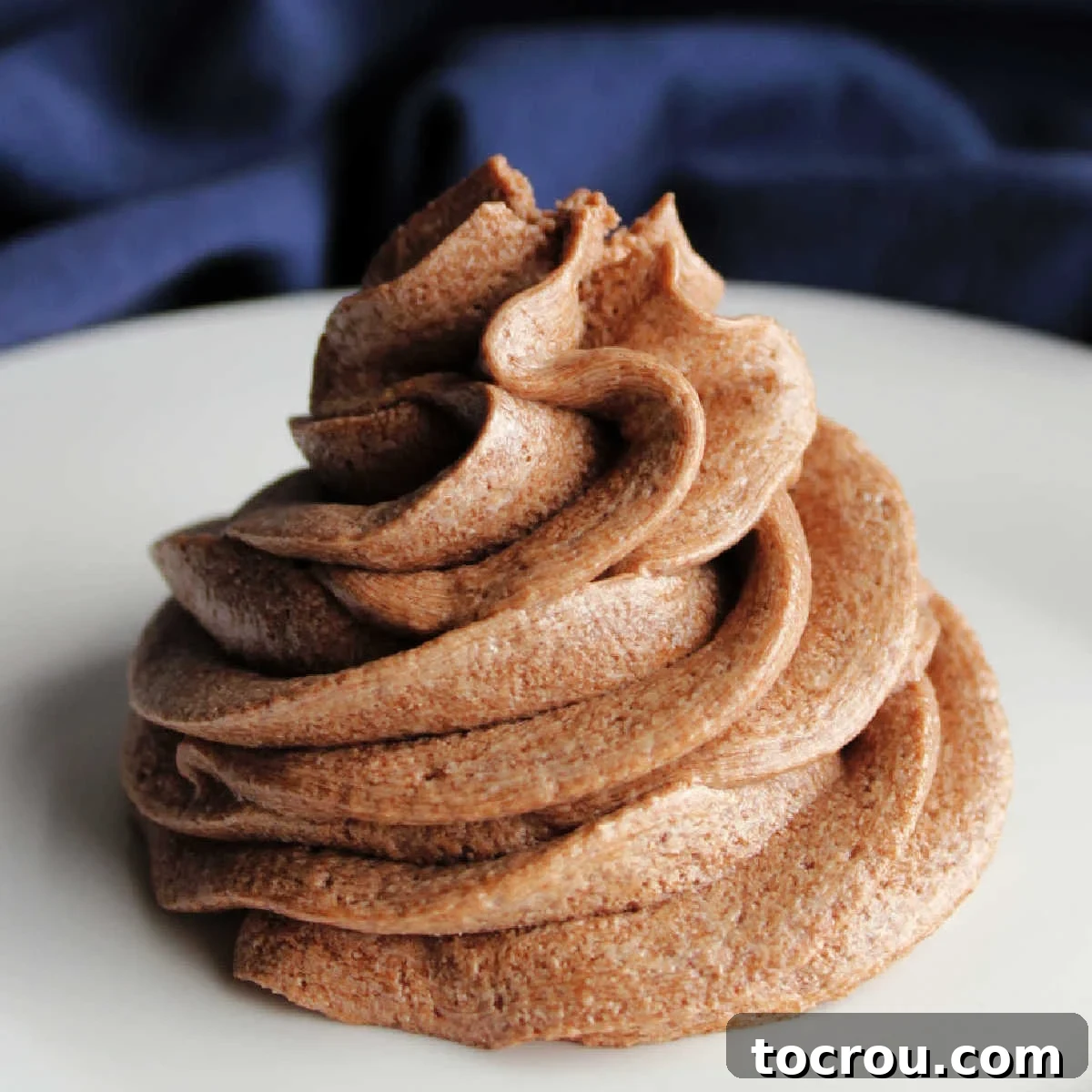 If you are looking for a soft, airy frosting with big mocha flavor, this recipe is for you! It is a cooked frosting with a butter base but ends with the texture of whipped cream. You have to give it a try! Pipe swirl of fluffy brown ermine frosting flavored with chocolate and coffee.